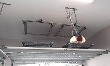 The Auxx Lift mid-operation, shown partially lowered with visible cable tension and platform alignment