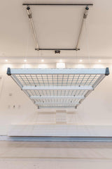 Front view of the Auxx Lift Platform Storage Lift installed in a garage, holding multiple storage bins