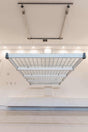 Front view of the Auxx Lift Platform Storage Lift installed in a garage, holding multiple storage bins
