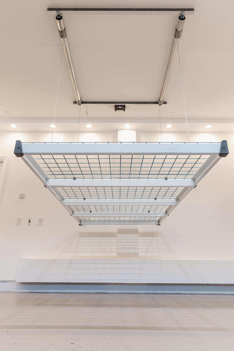 Front view of the Auxx Lift Platform Storage Lift installed in a garage, holding multiple storage bins
